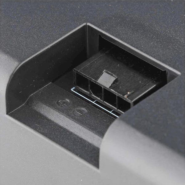 Detailansicht eines Akku-Anschlusses aus Kunststoff mit Plus- und Minus-Symbolen.