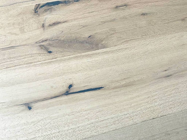 Nahaufnahme eines Holzbodens mit Maserung, Astlöchern und gefüllten Rissen.