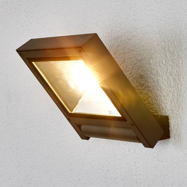 Dunkelgraue, rechteckige Außenwandleuchte mit LED und Bewegungsmelder, montiert an einer Wand und eingeschaltet.