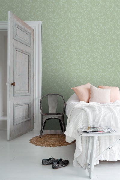 Schlafzimmer mit floral gemusterter Tapete, Bett und Tür