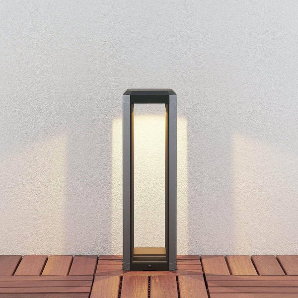 Moderne LED-Wegeleuchte in Anthrazit auf einer Holzterrasse vor einer hellen Fassade, minimalistisches Rahmendesign.