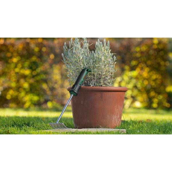 Gartenrechen und bepflanzter Topf im Garten