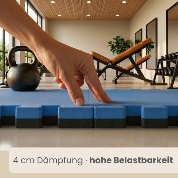 Hand prüft die 4 Zentimeter dicke Dämpfung einer ineinandergreifenden Bodenmatte in einem Fitnessraum mit Sportgeräten.