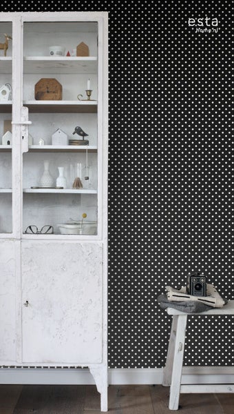 Dekoratives Wohnambiente mit weißem Schrank und gepunkteter Tapete