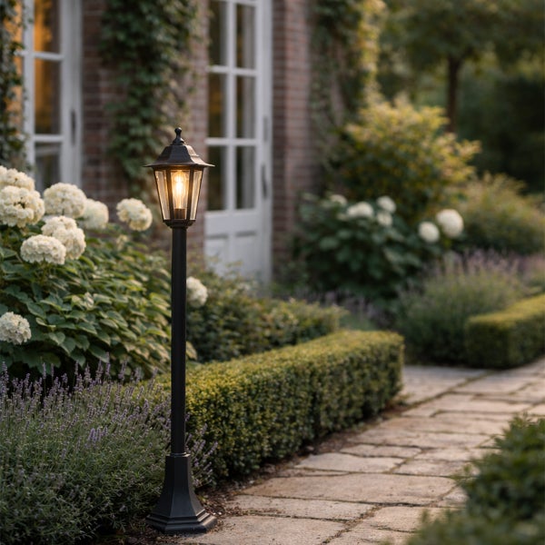 Schwarze Wegeleuchte im klassischen Laternen-Stil an einem Gartenweg mit weißen Hortensien und Lavendel.