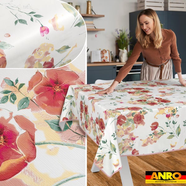 Wachstuch-Tischdecke mit Blumenmuster wird von einer Frau in einer hellen Küche auf einen Tisch gelegt. Detailansicht der Struktur. ANRO Logo.