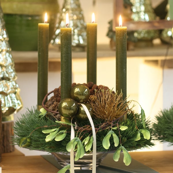Adventskranz mit vier brennenden Kerzen, Tannenzweigen, Kugeln und Schleife
