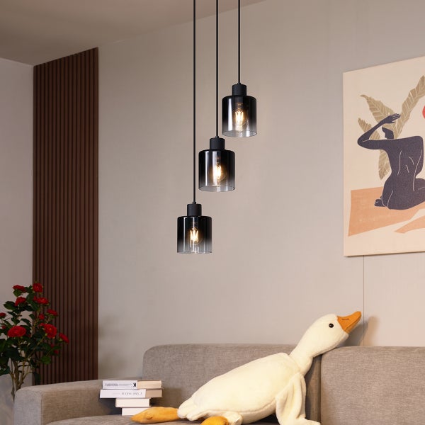 Drei schwarze Hängelampen mit Glaskörper über einem Wohnbereich.