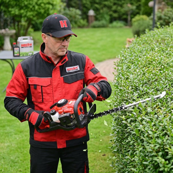 Eine Person schneidet eine Hecke mit einer Heckenschere von Hecht Garten.