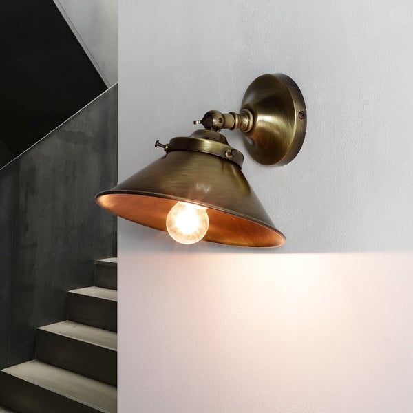 Wandleuchte mit konischem Lampenschirm und eingeschalteter Glühbirne neben einer Treppe