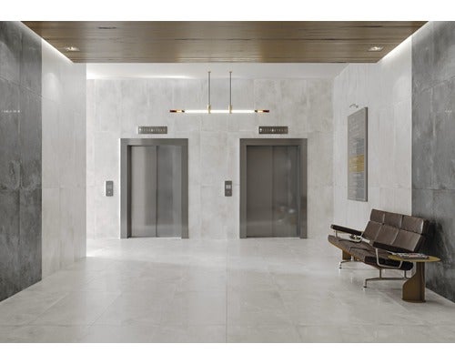 Helle Fliesen in einem modernen Flur mit Aufzügen und Sitzgelegenheiten.