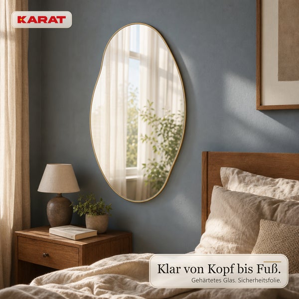 Wandspiegel mit unregelmaessiger Form und schmalem Rahmen in einem Schlafzimmer mit Holzmoebeln und Karat Logo.