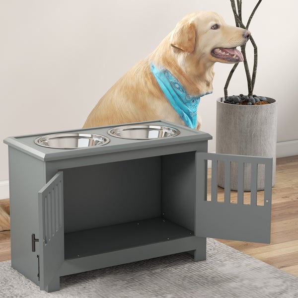 Graue Futterstation aus Holz mit zwei Edelstahlnäpfen und Unterschrank für Hundefutter, neben einem Hund in einem hellen Zimmer.