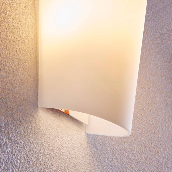Moderne Wandleuchte mit geschwungenem Schirm aus satiniertem Glas, an einer strukturierten Wand montiert, strahlt warmes Licht aus.