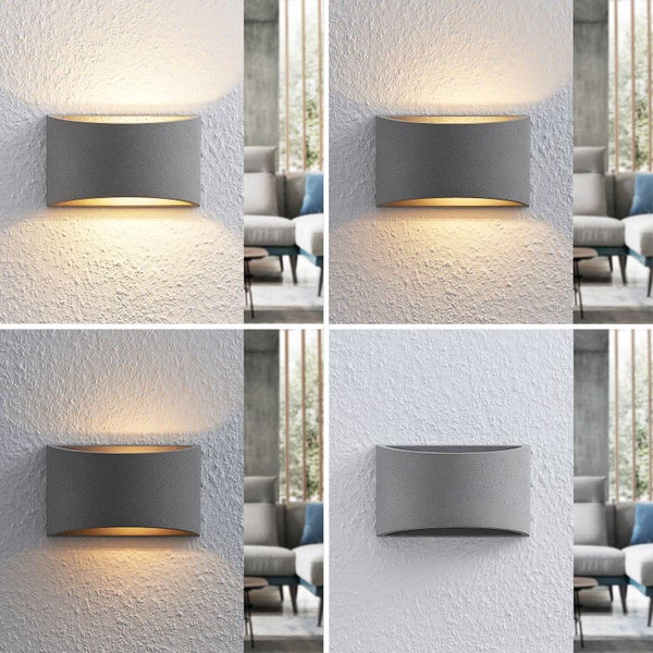 Wandleuchte aus Beton mit Up-and-Down-Beleuchtung an einer strukturierten Wand in einem hellen Wohnzimmer.