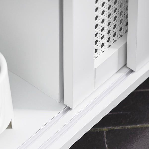 Detailaufnahme eines weißen Schranks mit Schiebetüren und Rattanmuster