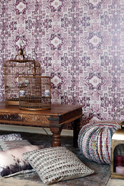 Dekorative Szene mit Mustertapete, Holztisch, Vogelkäfigen und Kissen