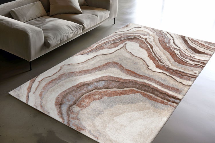 Rechteckiger Teppich mit abstraktem Wellenmuster in Erdtönen vor einem Sofa in einem modern gestalteten Wohnraum.