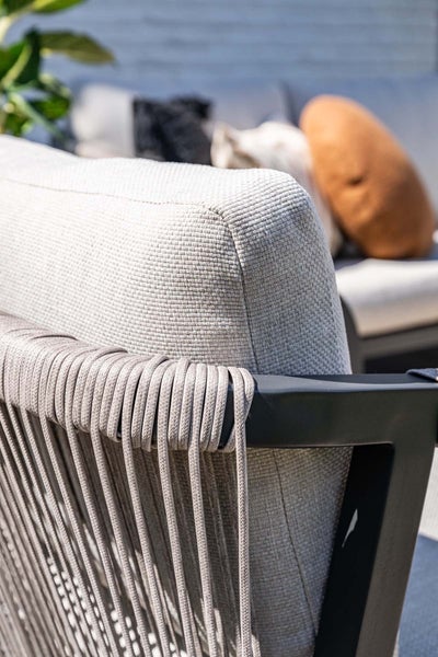 Nahaufnahme eines Garten-Loungesessels mit strukturiertem Kissen und einem mit Seil umwickelten Rahmen.