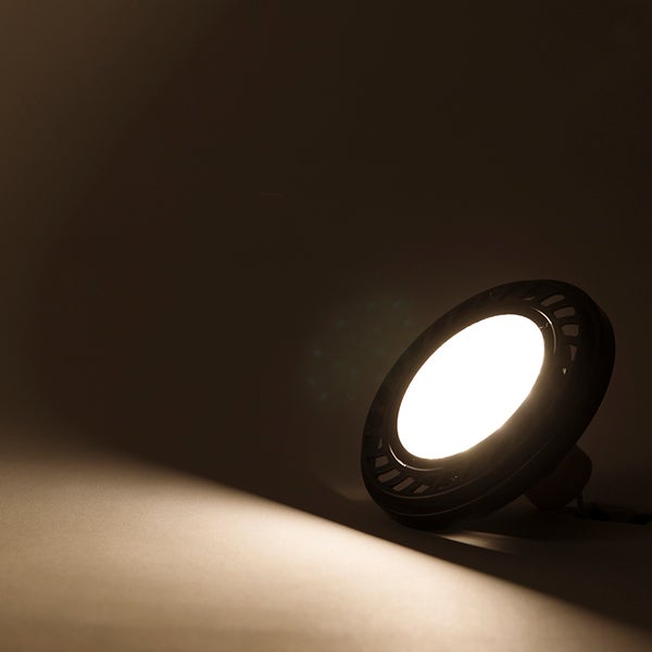 Eingeschaltete LED-Lampe mit warmweißem Lichtstrahl und schwarzem Gehäuse.