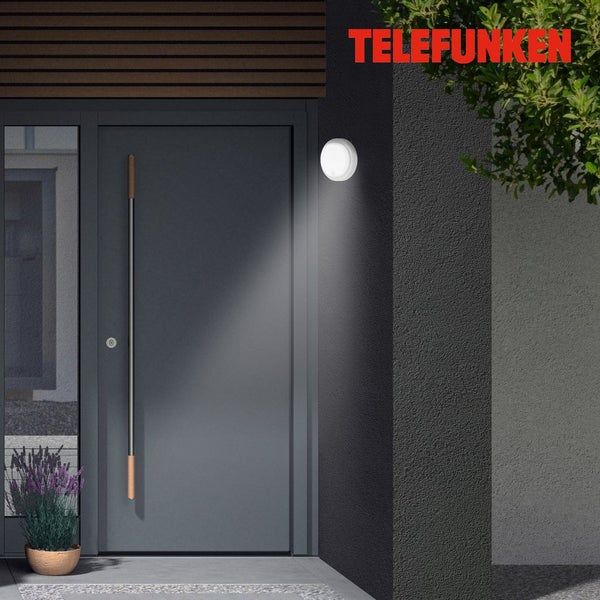 Telefunken Logo. Runde Außenwandleuchte an einer Fassade, die einen modernen Eingangsbereich mit Haustür beleuchtet.