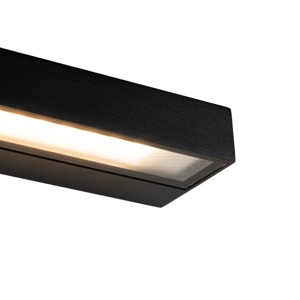 Nahaufnahme einer schwarzen, rechteckigen LED-Leuchte mit matter Abdeckung und warmem Licht.