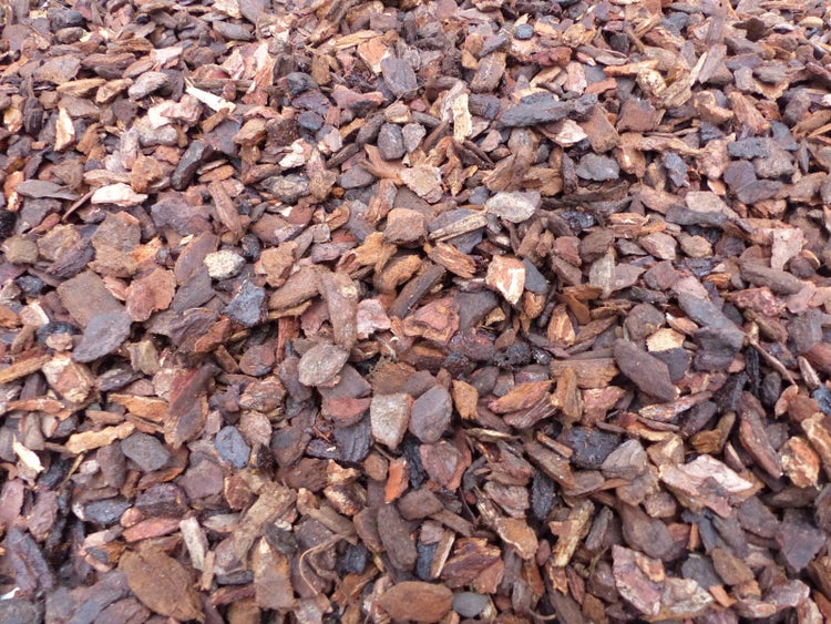 Grober Rindenmulch zur Bodenabdeckung und zum Schutz vor Unkraut im Garten.