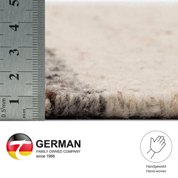 Detailansicht eines Teppichs mit Messskala zur Darstellung der Florhöhe. Das Bild zeigt außerdem das German Family Owned Company Logo und das Handweb-Symbol.