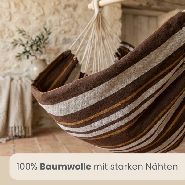 Gestreifter Hängesessel aus 100 Prozent Baumwolle mit starken Nähten in einem rustikalen Ambiente.