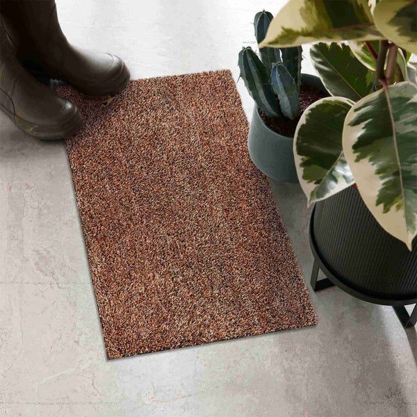 Fußmatte aus Textilfasern neben Gummistiefeln und Pflanzen