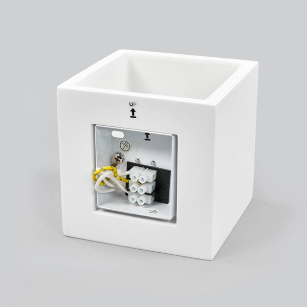 Rückansicht einer würfelförmigen Wandleuchte mit Montagehalterung und Lüsterklemme für den Elektroanschluss.