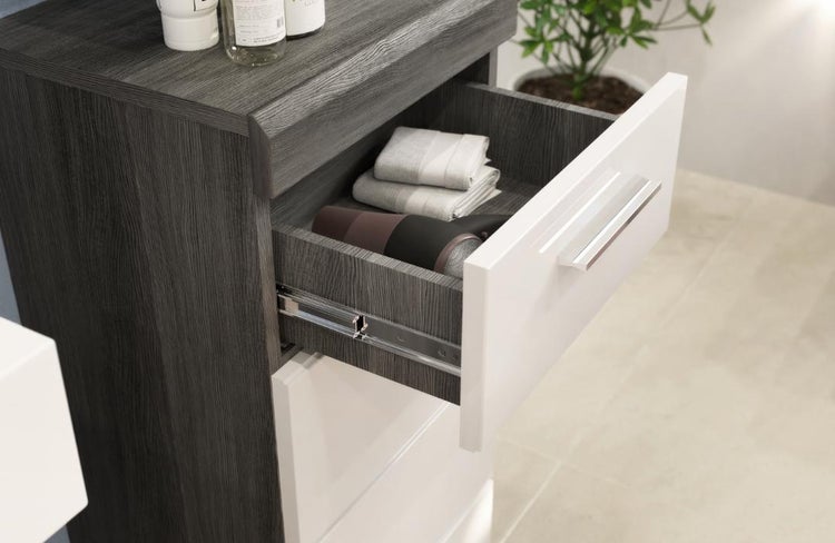 Moderner Bad-Mittelschrank mit dunkelgrauem Korpus in Holzoptik und einer geöffneten weißen Schublade mit silbernem Griff.