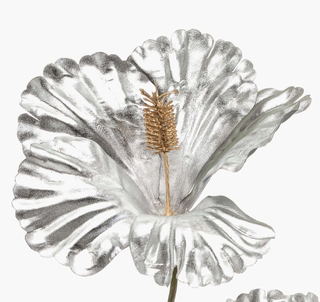Künstliche Pflanze mit braunem Stamm und grünen Blättern in einem schwarzen Kunststofftopf.