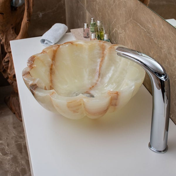 Modernes Badezimmer mit Naturstein-Aufsatzwaschbecken in Blütenform auf weißer Platte und hoher Chromarmatur, hell und organisiert gestaltet.