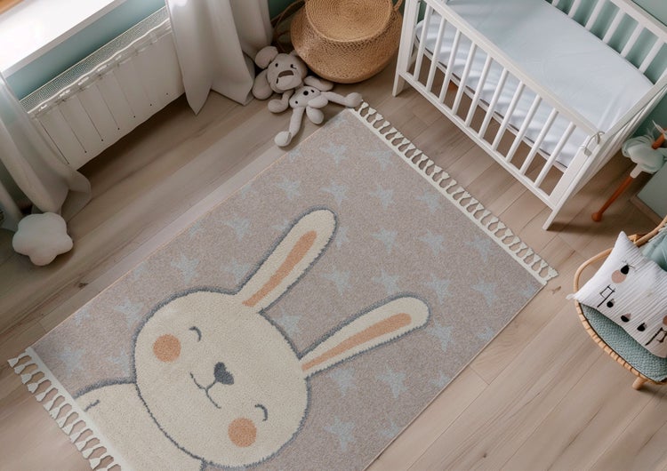 Kinderteppich mit Hasenmotiv und Sternenmuster sowie Fransen im Kinderzimmer vor einem Babybett