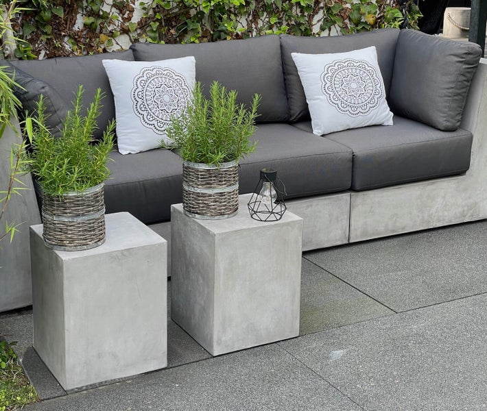 Graues Outdoor-Sofa mit Kissen, Beistelltischen und Pflanzen