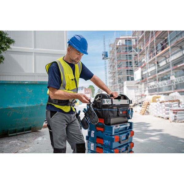 Handwerker auf einer Baustelle mit Bosch Werkzeugtasche GWT 20 auf gestapelten Bosch L-BOXX Koffern.