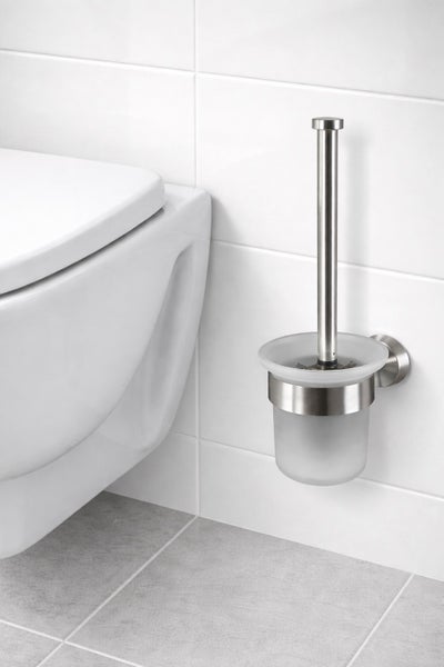 Wandmontierte Toilettenbürstengarnitur aus Edelstahl und mattiertem Glas neben einer weißen Toilette in einem modernen, hellen Badezimmer.