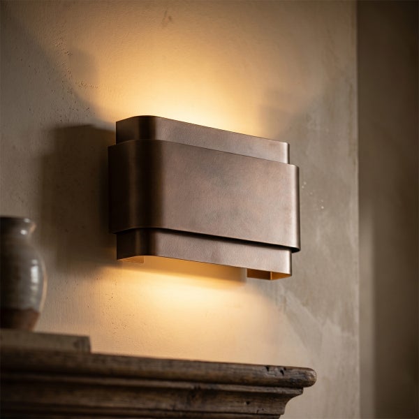 Moderne Wandleuchte in geschwungener Form aus Metall mit warmem indirektem Licht an einer Wand montiert