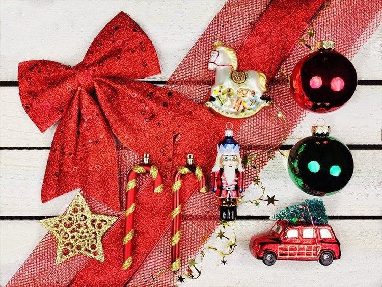 Weihnachtsbaumschmuck bestehend aus Glasanhängern wie Schaukelpferd, Nussknacker, Auto, Zuckerstangen und Weihnachtskugeln auf Holzgrund