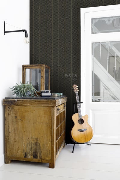 Dekorative Tapete mit Pfeilmuster in einem Wohnraum, mit Kommode und Gitarre