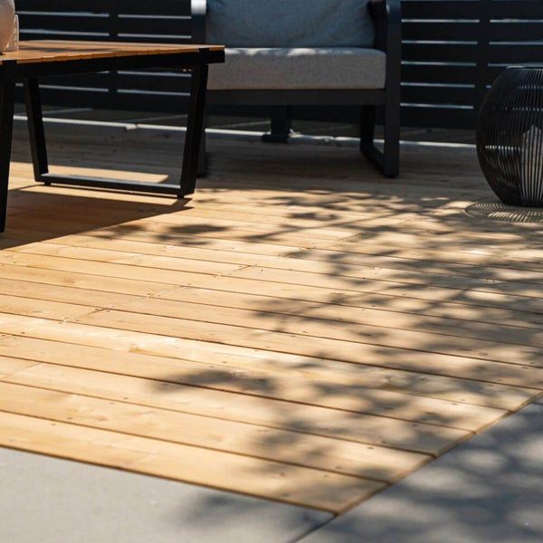 Holzterrasse mit strukturierten Terrassendielen aus Nadelholz mit einem Gartentisch und einem Stuhl vor einem Sichtschutz auf einer Terrasse
