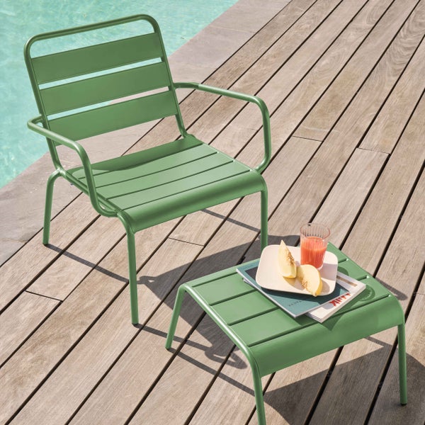 Grüner Garten-Loungesessel und Beistelltisch aus Metall auf einer Holzterrasse an einem Pool.