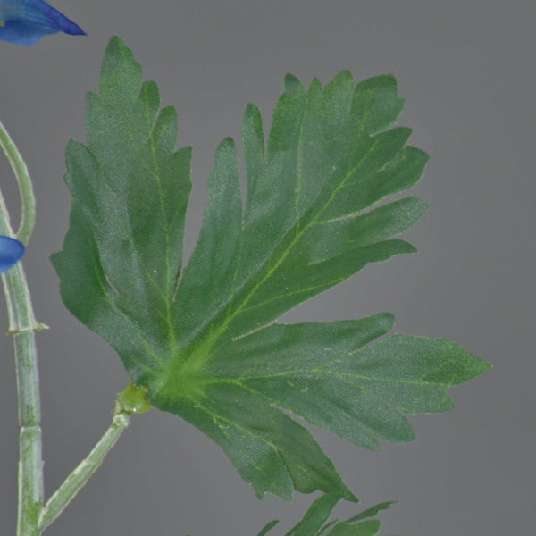 Detailansicht eines grünen Blattes einer Kunstpflanze mit gezacktem Rand.