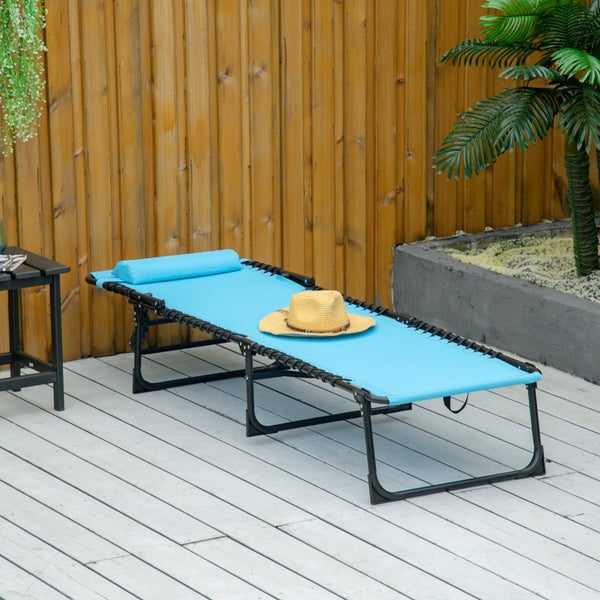 Frau entspannt auf einer blauen Sonnenliege mit schwarzem Metallgestell auf einer sonnigen Gartenterrasse mit Rasen und Haus im Hintergrund.