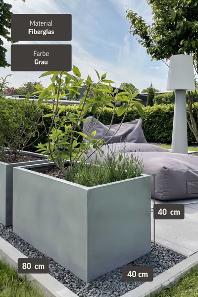 Organisierte Gartenszene mit modernen grauen Fiberglas Pflanzkästen 80 mal 40 mal 40 Zentimeter, Lavendel, Sitzsack und Außenleuchte.