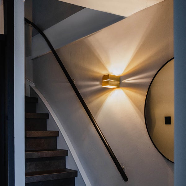 Eine Treppe mit einer quadratischen Wandleuchte, die Licht abstrahlt.