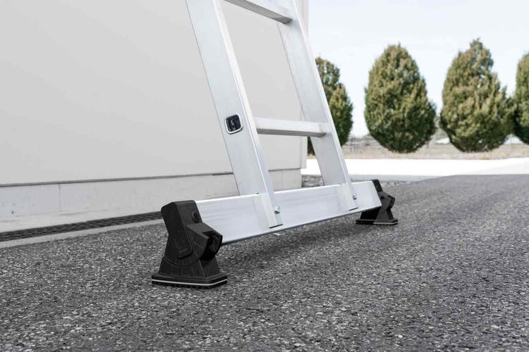 Detailansicht einer Aluminiumleiter mit schwarzen Fußstützen auf Asphalt.