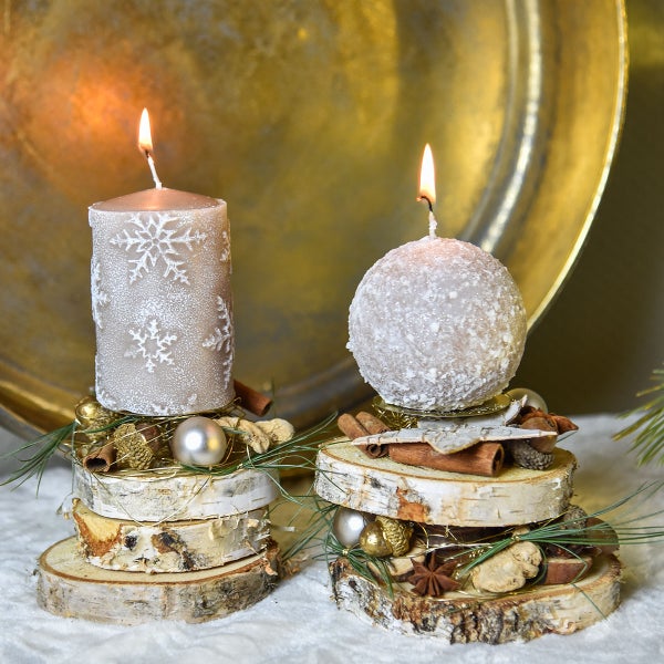 Zwei dekorative Kerzen auf Holzscheiben mit weihnachtlichen Verzierungen