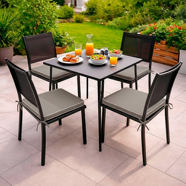 Gartenmöbel-Set bestehend aus einem quadratischen schwarzen Tisch und vier schwarzen Stühlen mit grauen Sitzkissen auf einer hellen Terrasse.